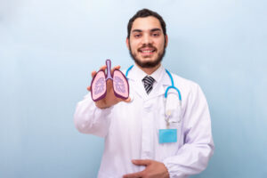médico sorrindo com um pulmão de brinquedo nas mãos